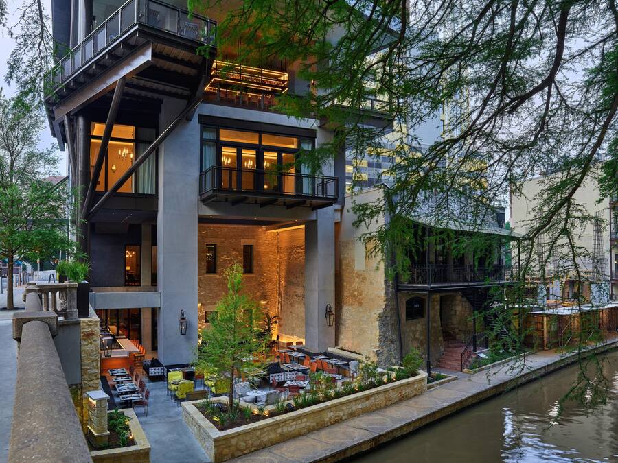 A modern building with a dining area, outdoor seating, and a water canal.