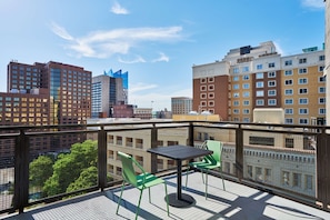Enjoy the city view from this balcony with a table and two chairs.