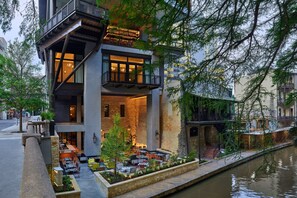 A modern building with a dining area, outdoor seating, and a canal. - Canopy San Antonio Riverwalk   (San Antonio)