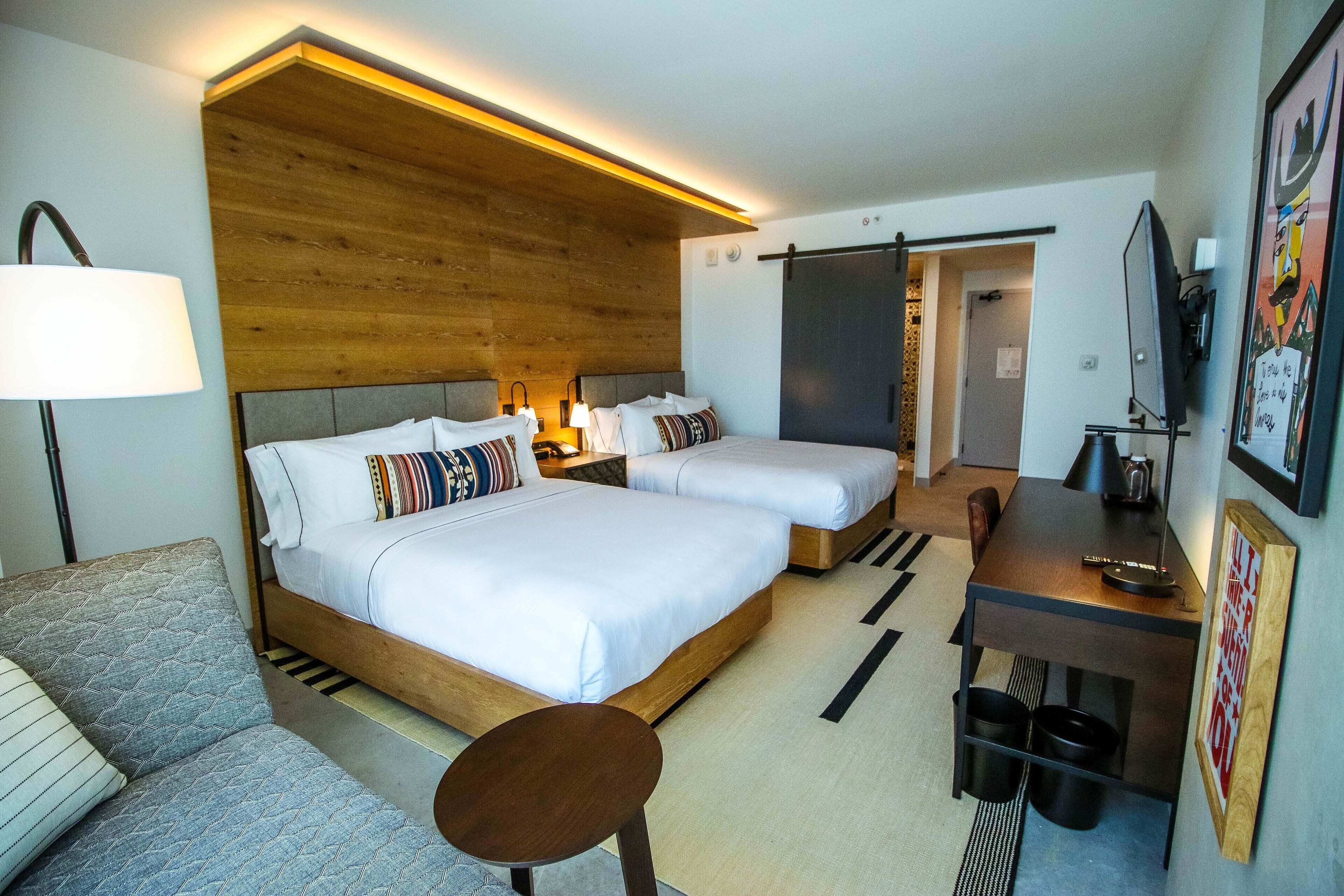Hotellihuone, jossa on suuri sänky, työpöytä, tuoli ja sohva.