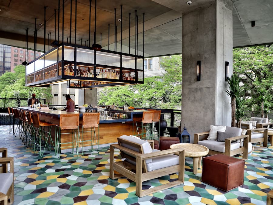 A bar area with a high counter, stools, and a seating area with sofas and tables.