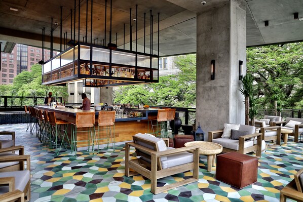 A bar area with a high counter, stools, and a seating area with sofas and tables. - Canopy San Antonio Riverwalk   (San Antonio)
