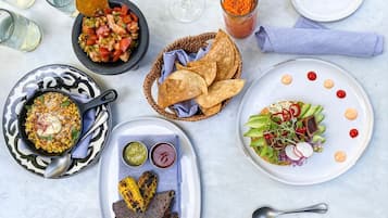 Eine Auswahl an Gerichten, darunter gegrillter Mais, ein Salat und eine Schüssel Salsa, die eine vielfältige Menüauswahl versprechen.