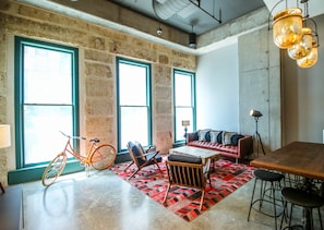 A spacious room with large windows, a red sofa, a wooden table, and a bicycle.