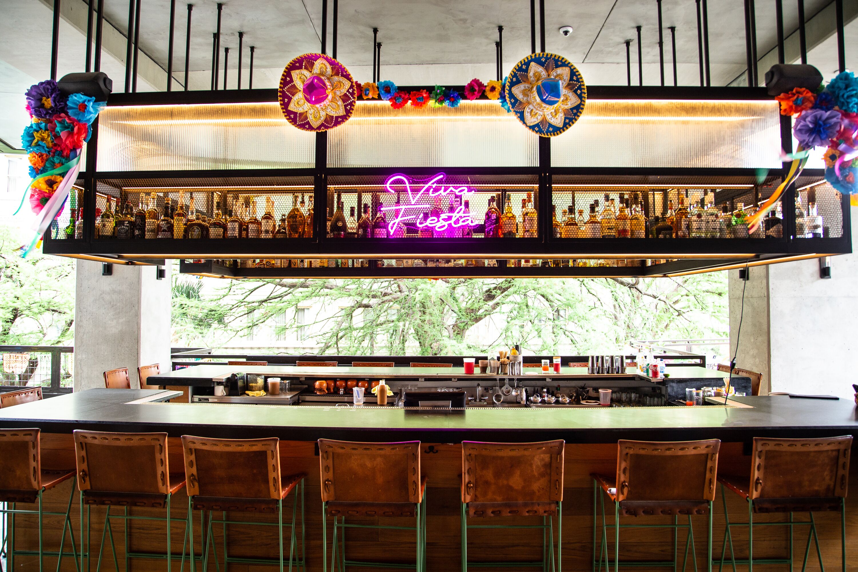 A bar area with a neon sign, wooden chairs, and a bar counter.
