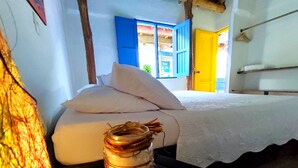 Een kamer met een bed, een nachtkastje, en een muur met een blauwe deur en een gele deur.
