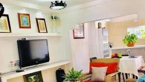 A living room with wicker furniture, a flat-screen TV, and a dining area with a table and chairs. - Casa Don Arturo (Santa Marta)