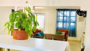 A spacious room with a white table, a potted plant, a wicker sofa, and a dining area with a table and chairs. - Casa Don Arturo (Santa Marta)
