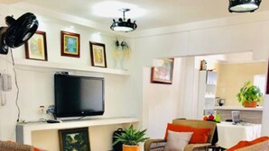 A living room with wicker furniture, a flat-screen TV, and a kitchen area in the background. - Casa Don Arturo (Santa Marta)