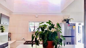 A modern kitchen with a central island, a refrigerator, and a window. - Casa Don Arturo (Santa Marta)