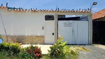 A building with a white exterior, a tiled roof, and a gated entrance.