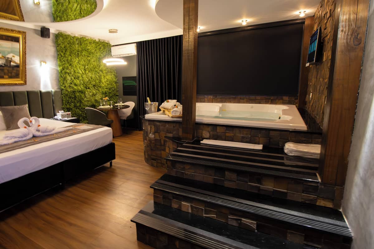 Ein modernes Hotelzimmer mit Bett, einer Sitzecke, einer grünen Wand, einem Kamin und einem Fernseher.