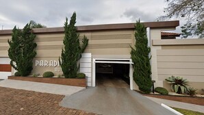 A modern building with a garage entrance, two tall trees, and a well-maintained garden.