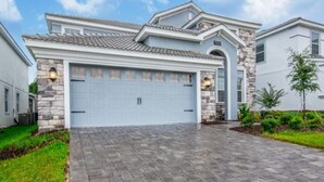 A residential house with a stone facade, a light blue garage door, and a paved driveway.