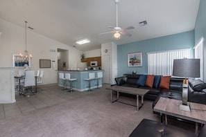 A modern living room with a sofa, coffee table, and dining area with chairs.