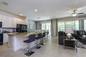A modern kitchen with white cabinets, a granite countertop, and a bar area with bar stools. - 8 Bedroom 5 Bathroom Bella Vida Resort 498mb (Kissimmee)
