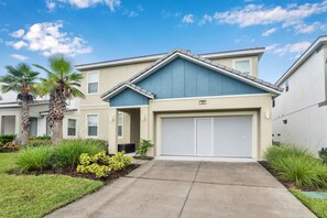 A two-story residential building with a garage, a well-maintained lawn, and palm trees. - 8 Bedroom 5 Bathroom Bella Vida Resort 498mb (Kissimmee)