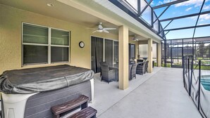 A covered patio area with a hot tub, seating, and a view of a swimming pool. - 8 Bedroom 5 Bathroom Bella Vida Resort 498mb (Kissimmee)