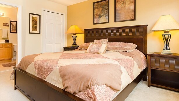 A bedroom with a large bed, two bedside lamps, and artwork on the walls. - 2753lkd Amazing 6 Bedroom Emerald Isle (Kissimmee)