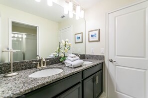 A bathroom with two sinks, a large mirror, and a door with a white frame. - 6 Bedroom Resort Villa With Spa (Davenport)