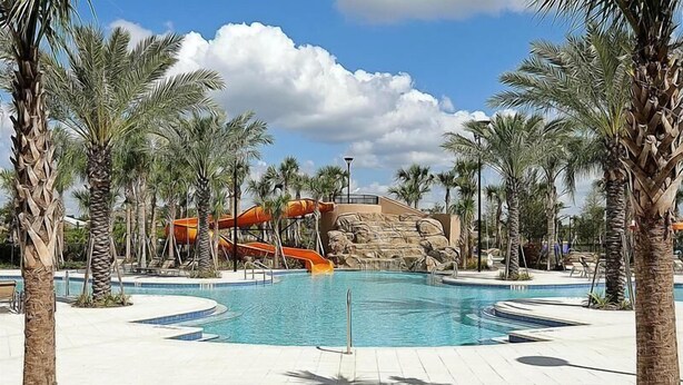 A swimming pool with palm trees, a water slide, and a rock formation. - Broad Oak Villa Solaterra (Davenport)