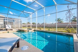 A pool area with a clear blue pool, a covered seating area, and a view of the surrounding landscape.