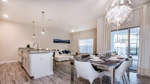 Una cocina moderna con comedor, armarios blancos y una isla grande.