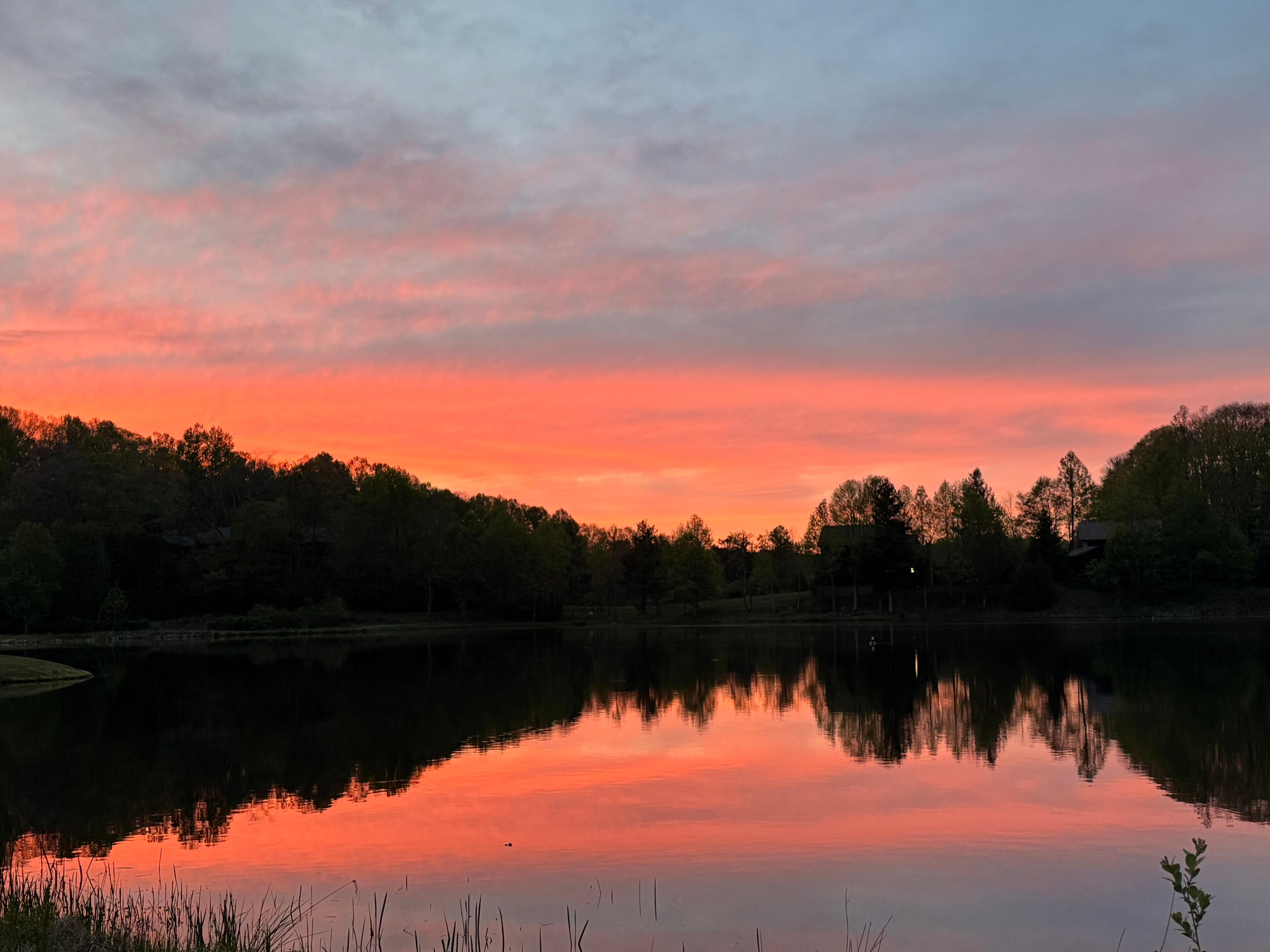 Un lac paisible au coucher du soleil, avec des arbres qui se reflètent dans le ciel.