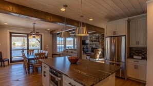 A spacious kitchen with a large island, wooden ceiling beams, and modern stainless steel appliances. - Lakeshore Retreat- new construction in Sweetgrass, right on the lake (Blowing Rock)