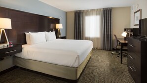 Une chambre d’hôtel avec un grand lit, deux tables de chevet avec des lampes, un bureau avec une chaise et un téléviseur.