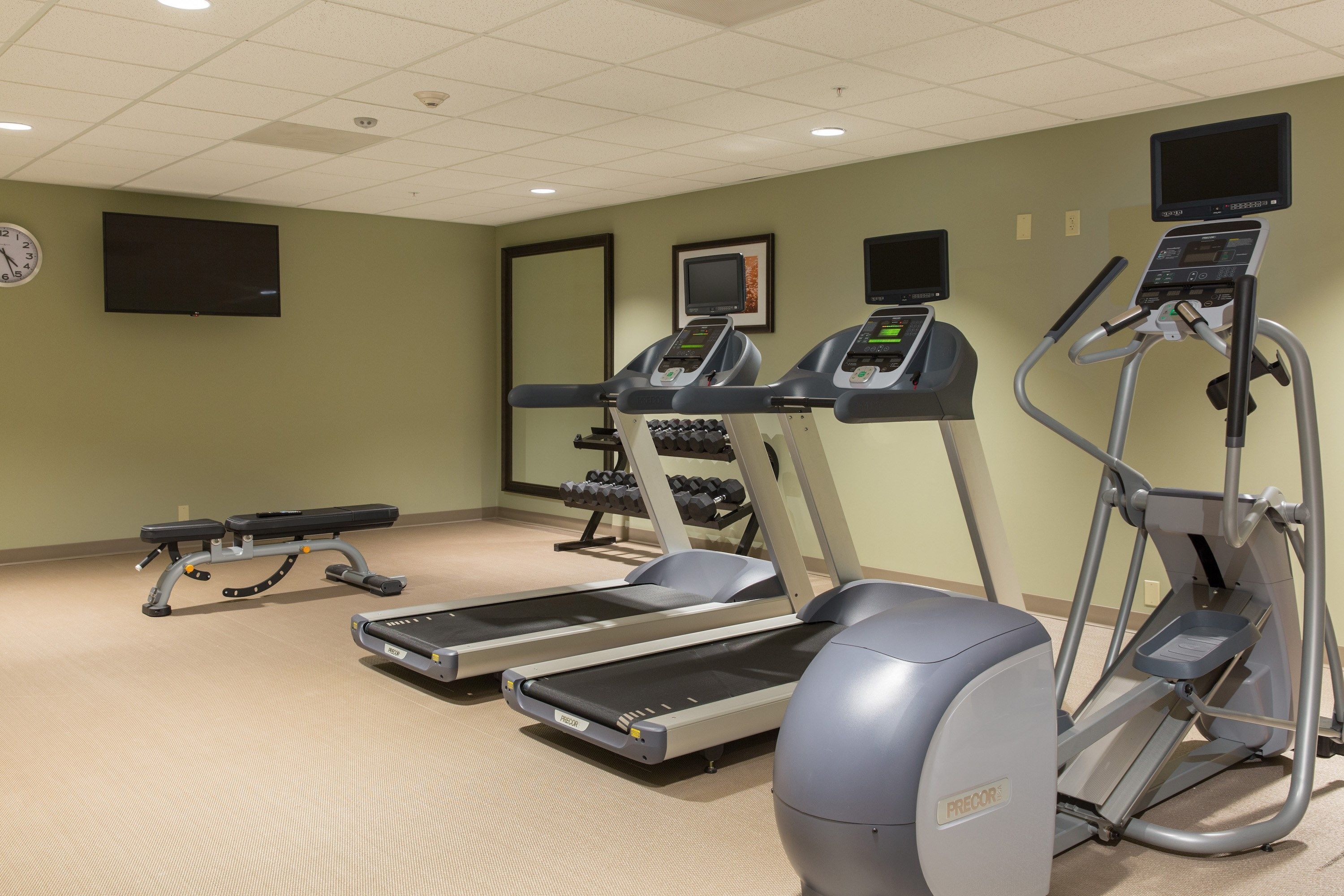 A fitness center with treadmills, an elliptical, and a bench.