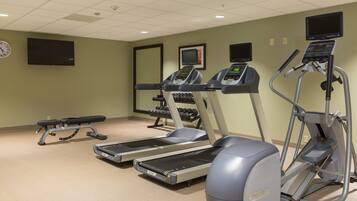 A fitness center with treadmills, an elliptical, and a bench.