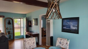 A dining area with a wooden table, blue placemats, and a pendant light. - The Williams Cottage (Carlsbad)