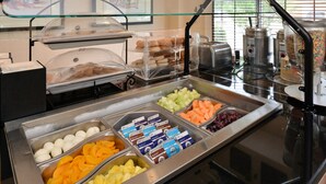 Un bufé con diferentes opciones de comida, entre ellas frutas, pastelería y bebidas.