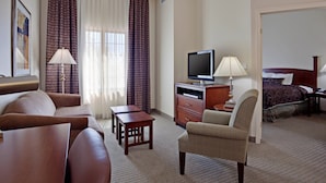 Een hotelkamer met een bank, fauteuil, televisie, bureau en een bed.