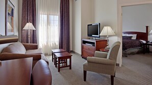 A hotel room with a sofa, armchair, TV, desk, and a bed. - Accessible 1BR w/ Roll-In Shower, Palmdale (Palmdale)