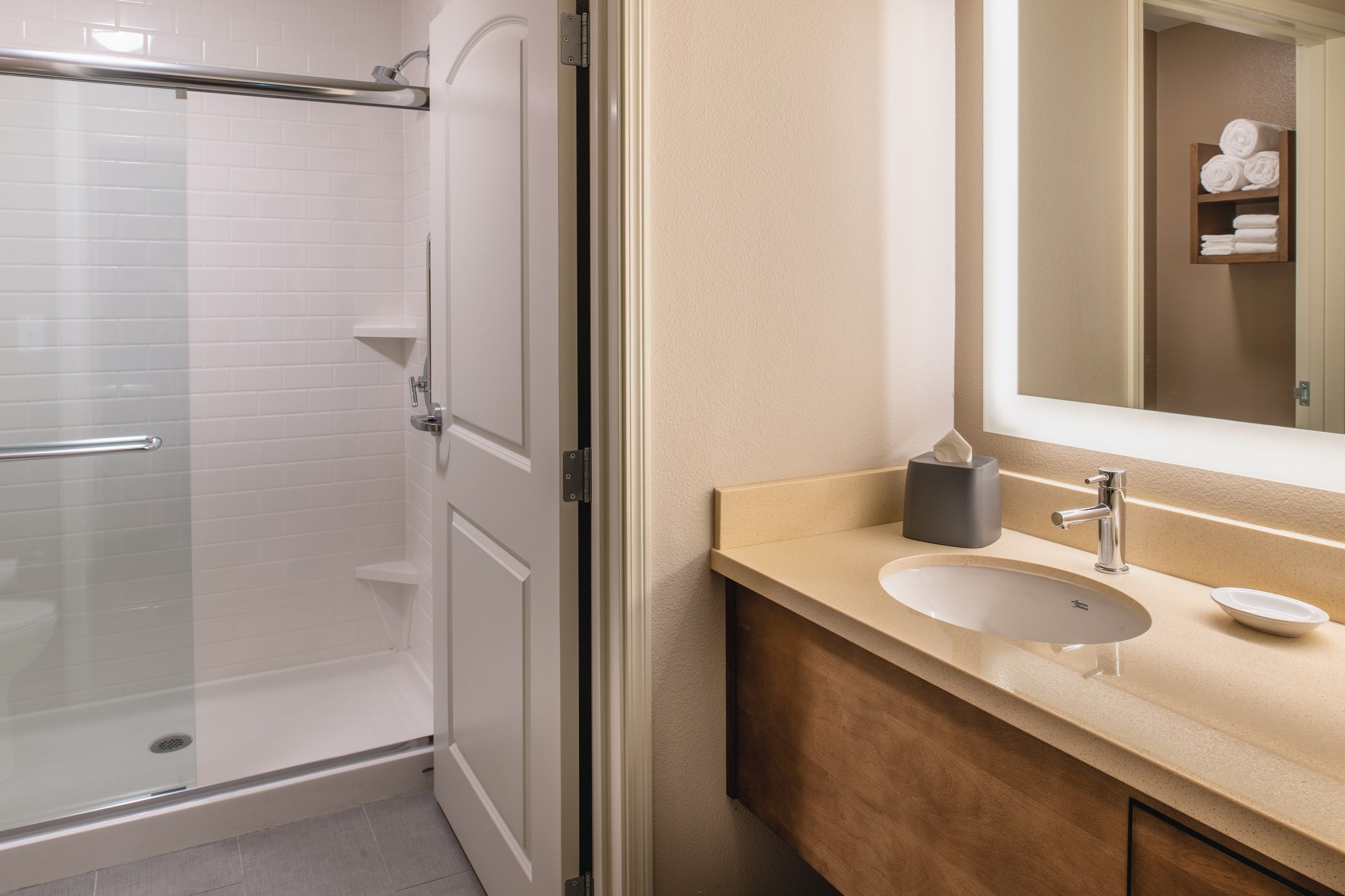 Une salle de bain avec une douche à parois de verre, un lavabo avec un miroir et un porte-serviettes avec des serviettes.