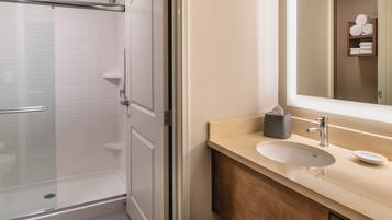 Une salle de bain avec une douche à parois de verre, un lavabo avec un miroir et un porte-serviettes avec des serviettes.