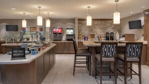 Una cocina moderna con barra desayunadora, televisor de pantalla plana y salpicadero de piedra.