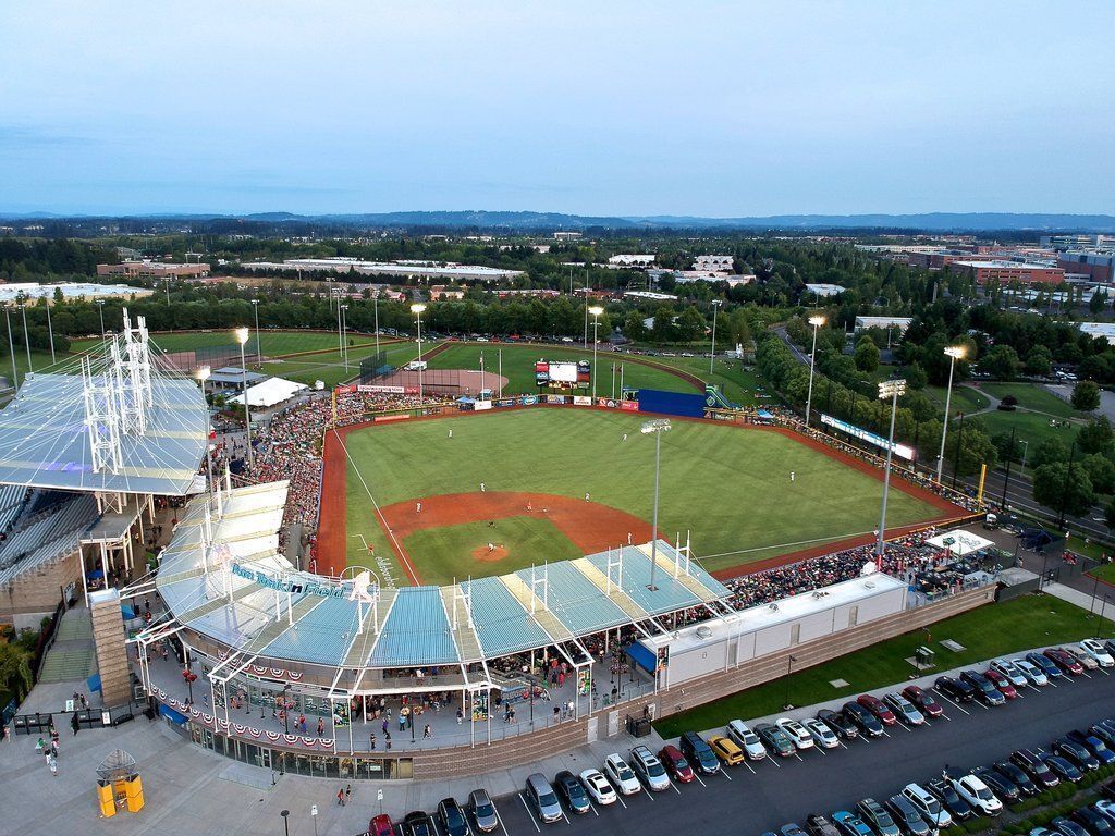 Ein Stadion mit Baseballfeld, Zuschauerbereichen und Parkplatz.