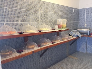 A breakfast buffet with covered food items and a sink area. - Pousada Casa Beneventi Jeri (Jijoca de Jericoacoara)