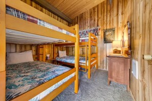Une cabane en bois avec des lits superposés, un petit bureau et une lampe.