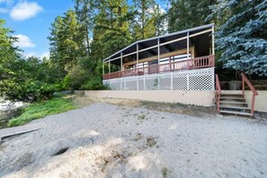 Une cabane dotée d’une terrasse couverte et d’un escalier menant à un deuxième niveau.