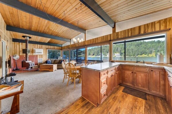 Une cuisine spacieuse avec des meubles en bois, un grand îlot central et une vue sur un lac.