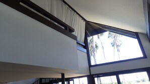 A modern interior with a large window, white curtains, and a view of palm trees outside. - Nature is waiting for you!   Explore, relax and enjoy it! (Crystal River)