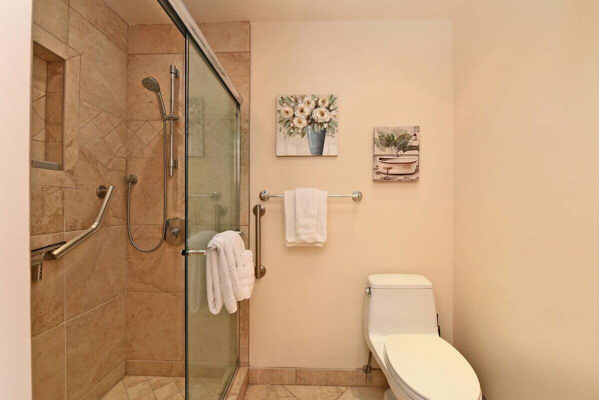A bathroom with a glass-enclosed shower, a toilet, and two wall-mounted towel racks.