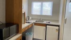 A compact kitchen with a microwave, toaster, sink, and a small refrigerator.