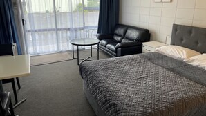 A hotel room with a bed, a sofa, a small table, and a window with curtains.