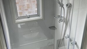 A glass-enclosed shower with a window, a towel rack, and a showerhead.