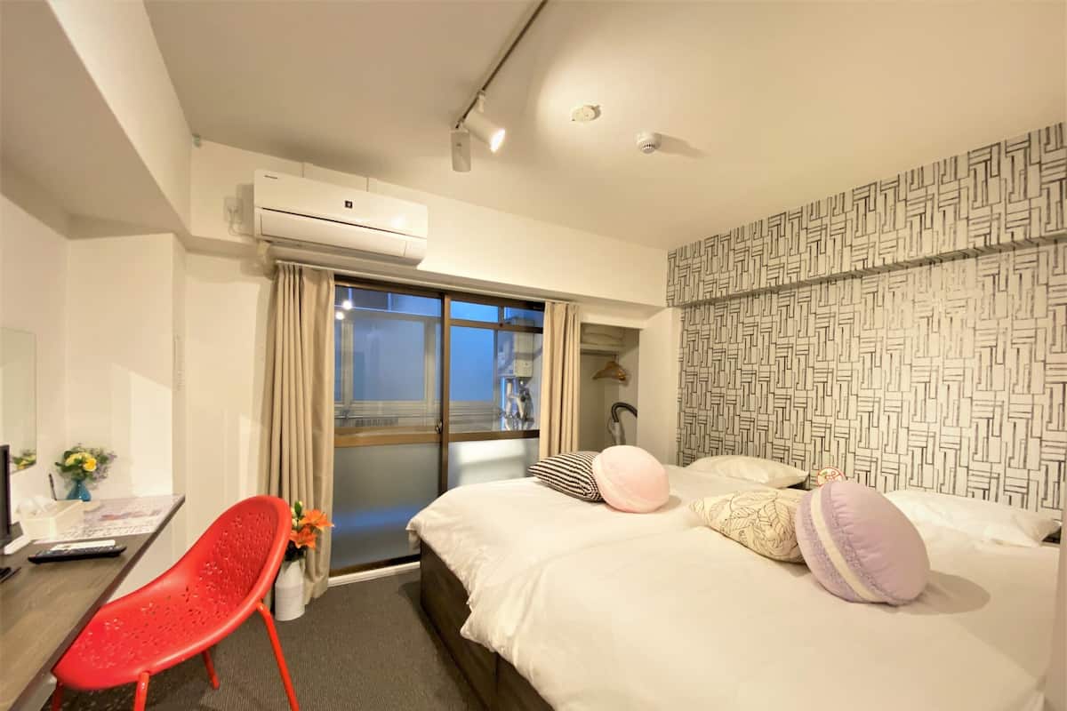 A hotel room with a bed, a desk, a chair, and a window with curtains.